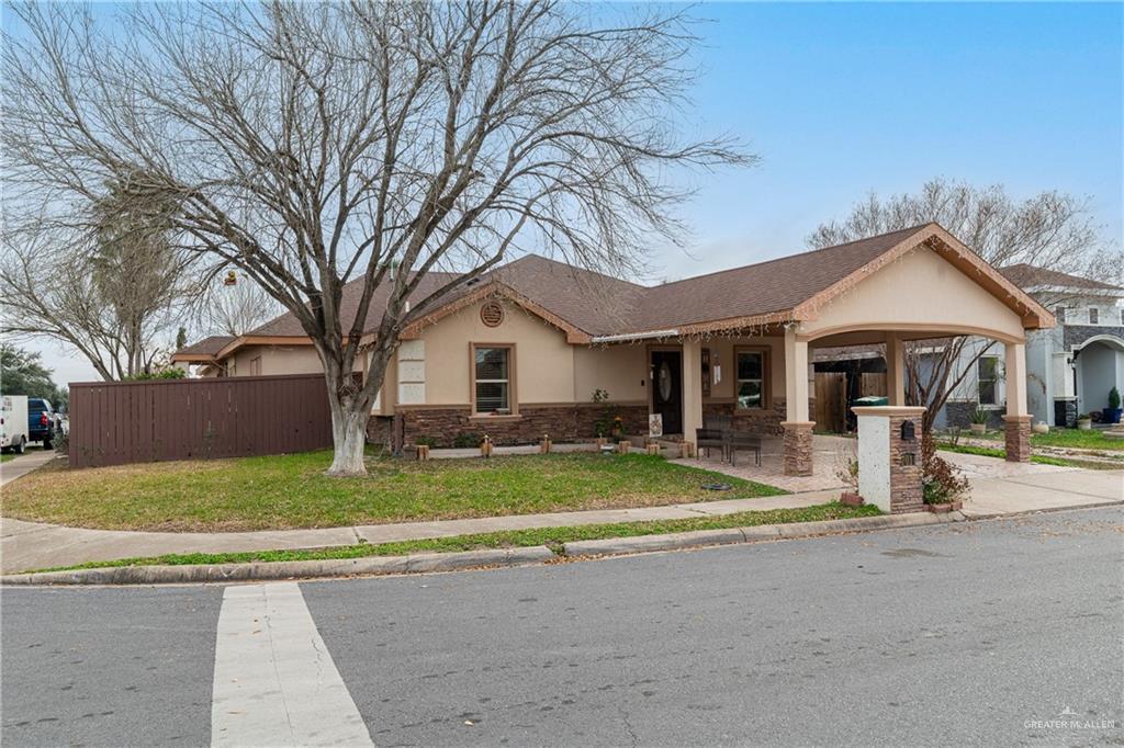 a view of a house with a yard and large tree