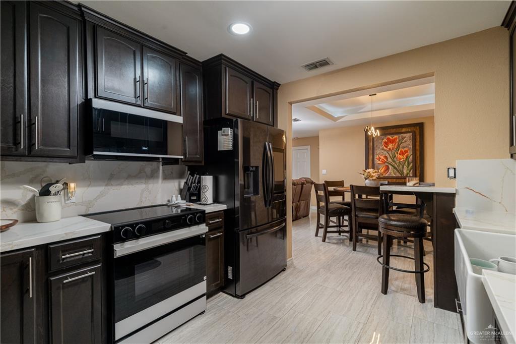 701 West Falcon Avenue Pharr, TX 78577 - Photo 7 of 24 a kitchen with granite countertop wooden cabinets dining table and stainless steel appliances