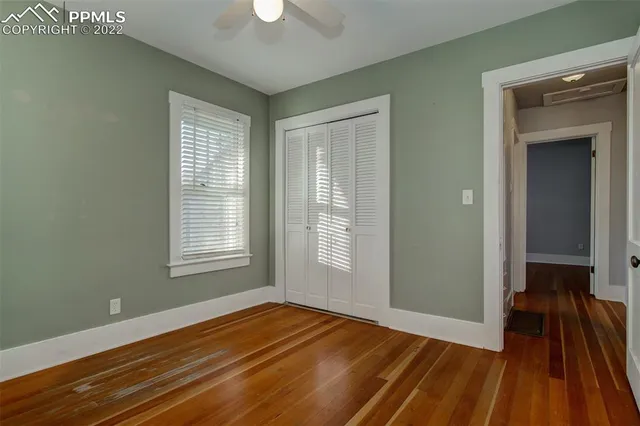 a view of empty room with wooden floor and fan
