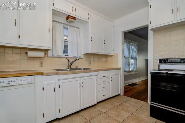 a kitchen with granite countertop white cabinets and stainless steel appliances