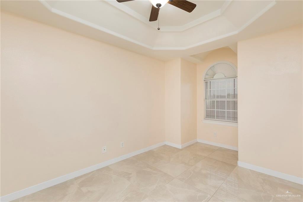 2001 Quail Lane Mission, TX 78572 - Photo 17 of 28 Tray ceiling with a ceiling fan, arched window, and large format tile flooring