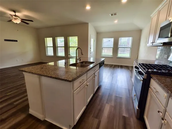 a kitchen with sink a stove and wooden floor
