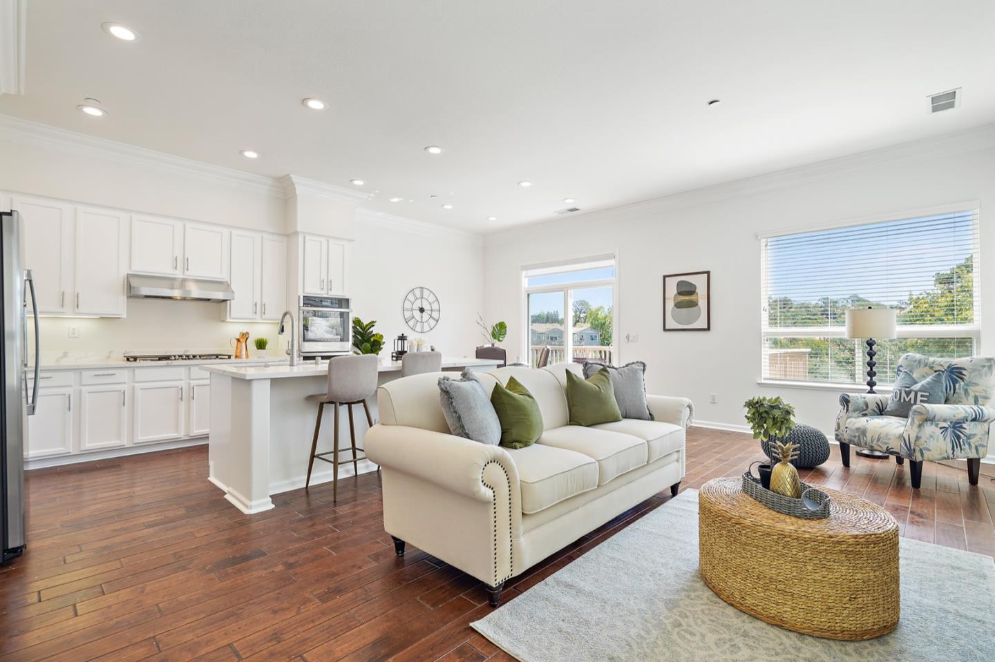 a living room with stainless steel appliances furniture and a kitchen view