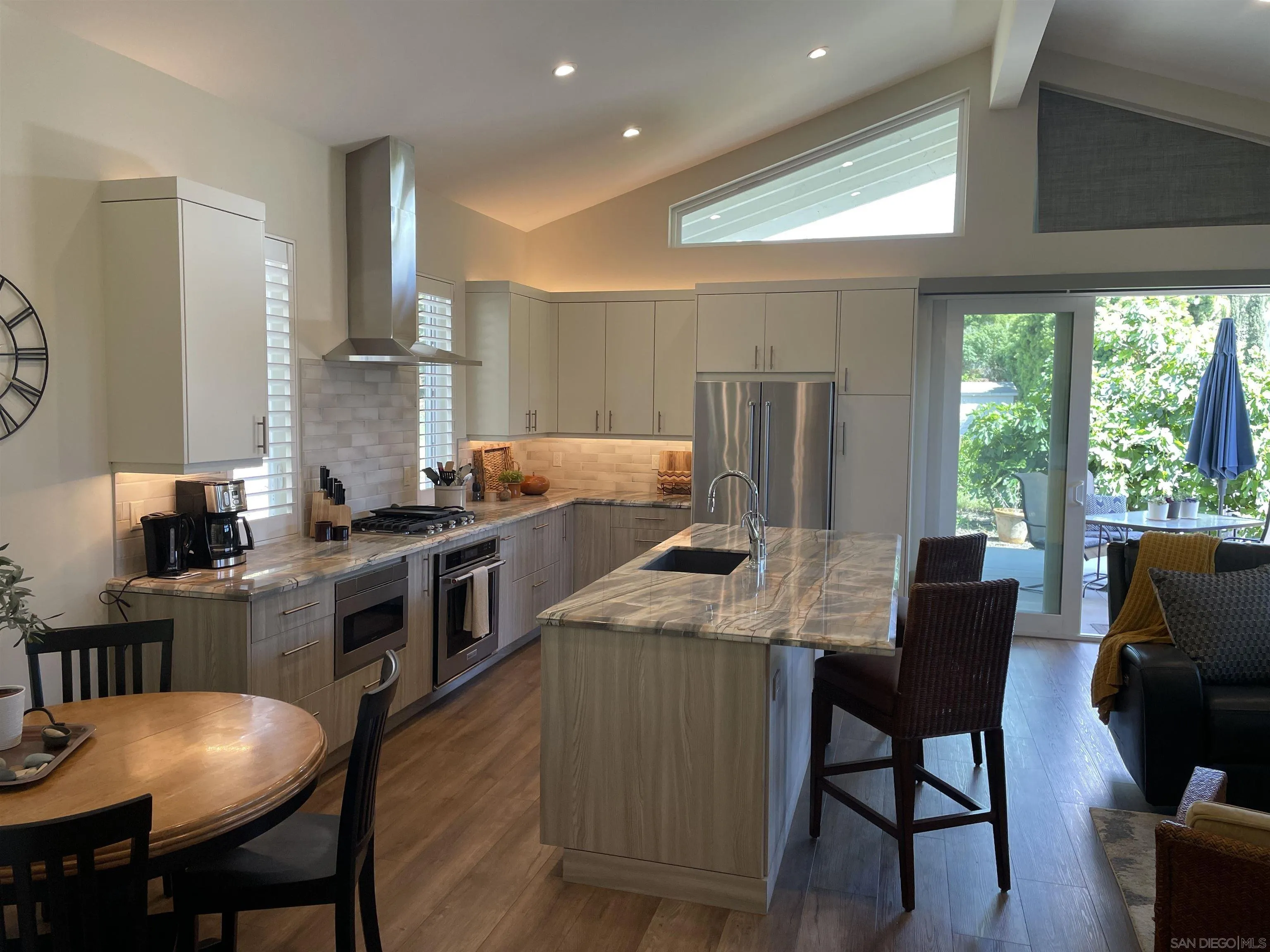 327 Cole Ranch Road Encinitas, CA 92024 - Photo 9 of 22 a kitchen with a table chairs refrigerator and cabinets