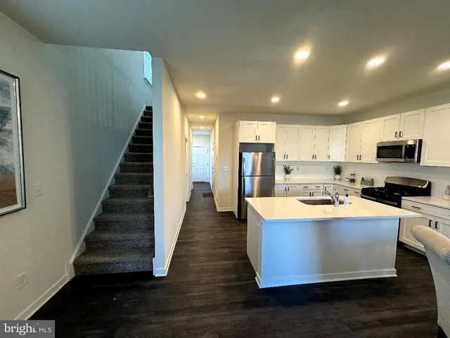 a view of a kitchen with wooden floor and stainless steel appliances