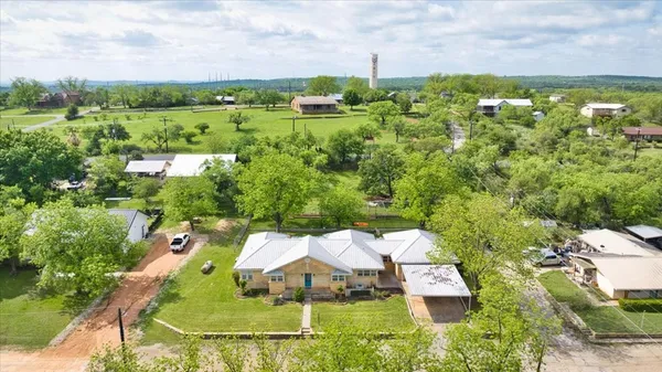 an aerial view of residential houses with outdoor space and trees