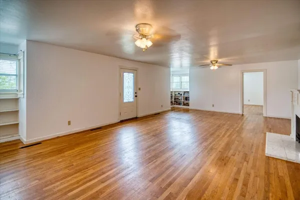 an empty room with wooden floor and windows