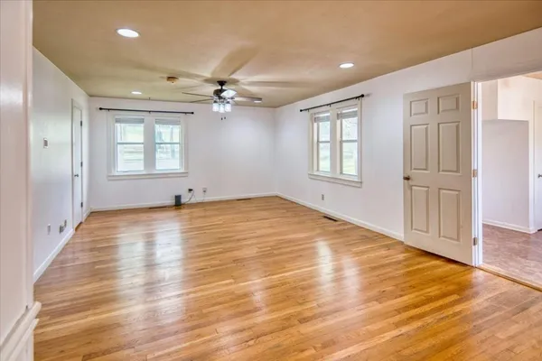 a view of empty room with wooden floor and fan