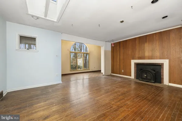 an empty room with wooden floor fireplace and windows
