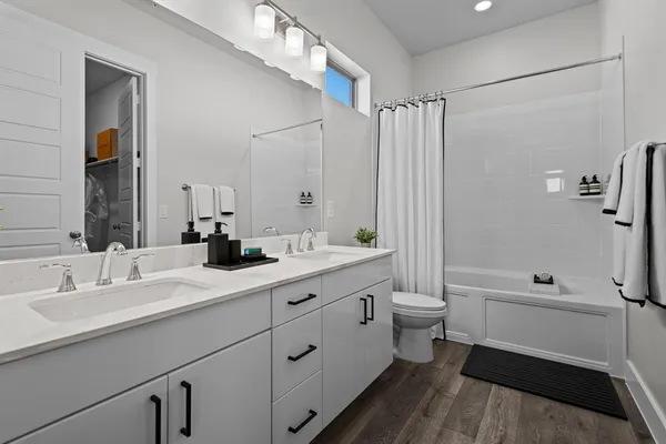 a bathroom with a double vanity sink toilet mirror and bathtub