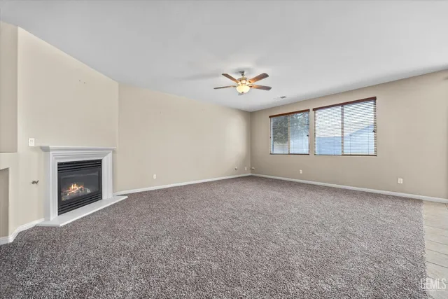 a view of an empty room with a window and fireplace
