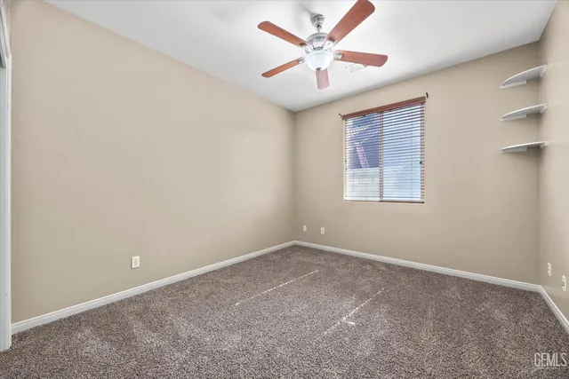 an empty room with closet and a ceiling fan