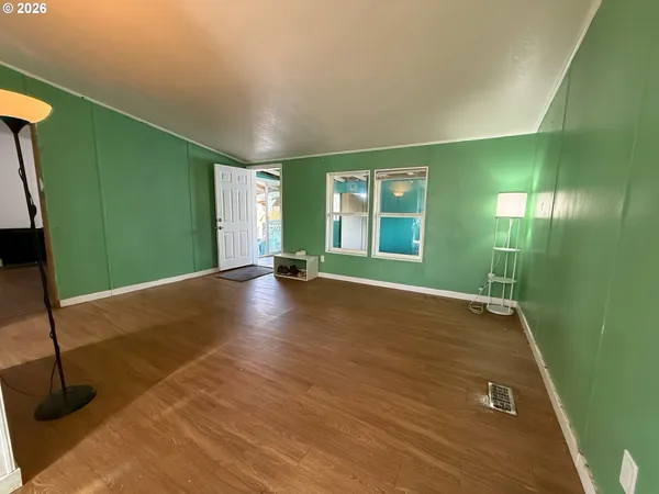 a view of an empty room with window and wooden floor