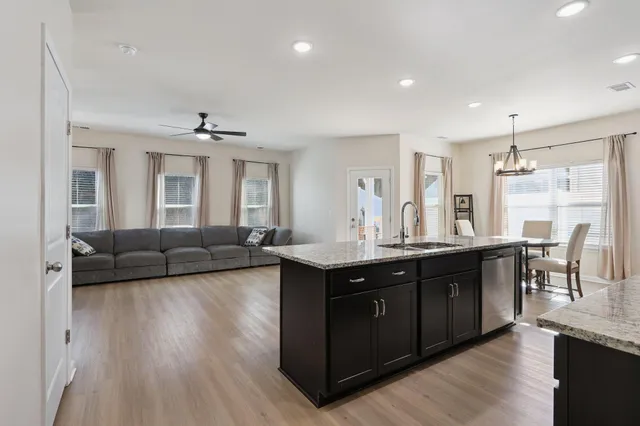 a living room with stainless steel appliances granite countertop furniture wooden floor and a sink