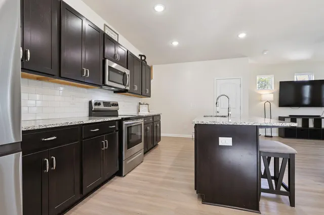 a kitchen with stainless steel appliances granite countertop a stove a sink and a refrigerator