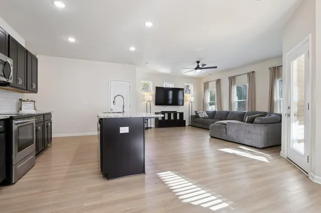 a living room with stainless steel appliances furniture and a kitchen view