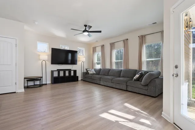 a kitchen with stainless steel appliances kitchen island granite countertop a stove a refrigerator a sink a microwave oven with white cabinets and wooden floor