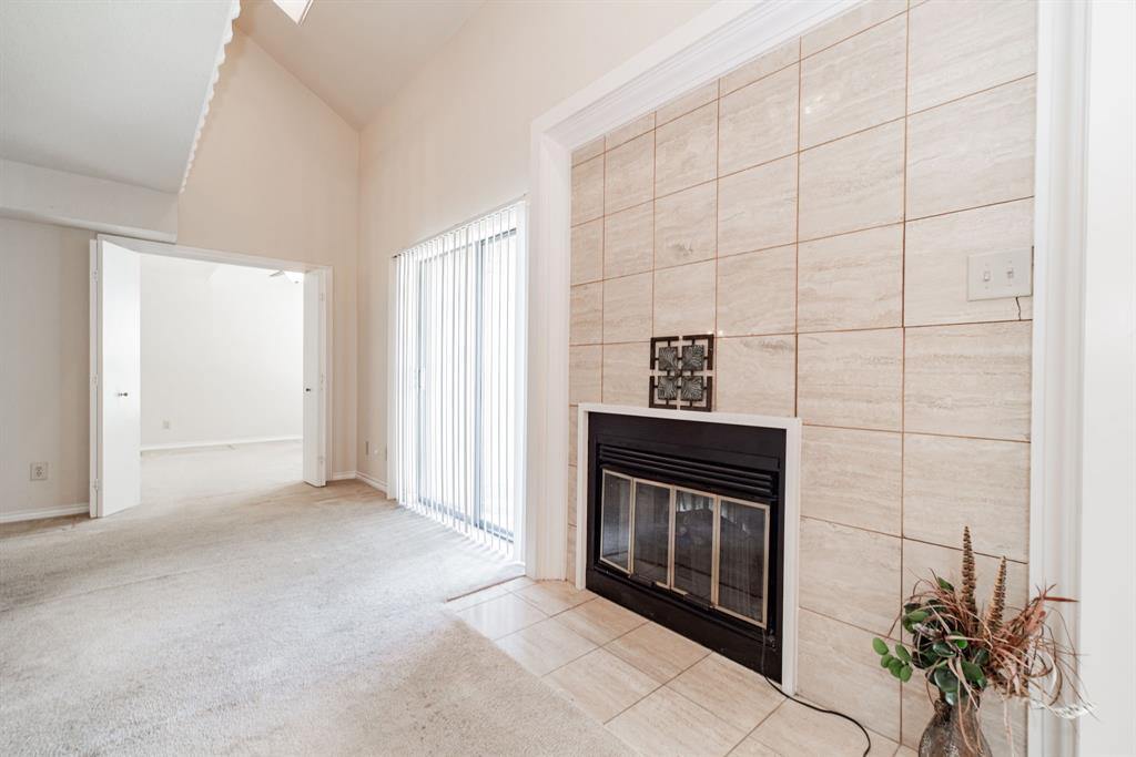 1106 Signal Ridge Place Rockwall, TX 75032 - Photo 6 of 32 Unfurnished living room with a tiled fireplace, carpet flooring, and vaulted ceiling