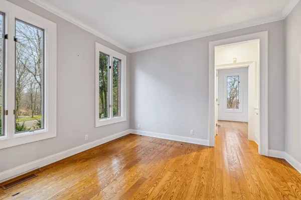 a view of an empty room with chandelier fan and wooden floor
