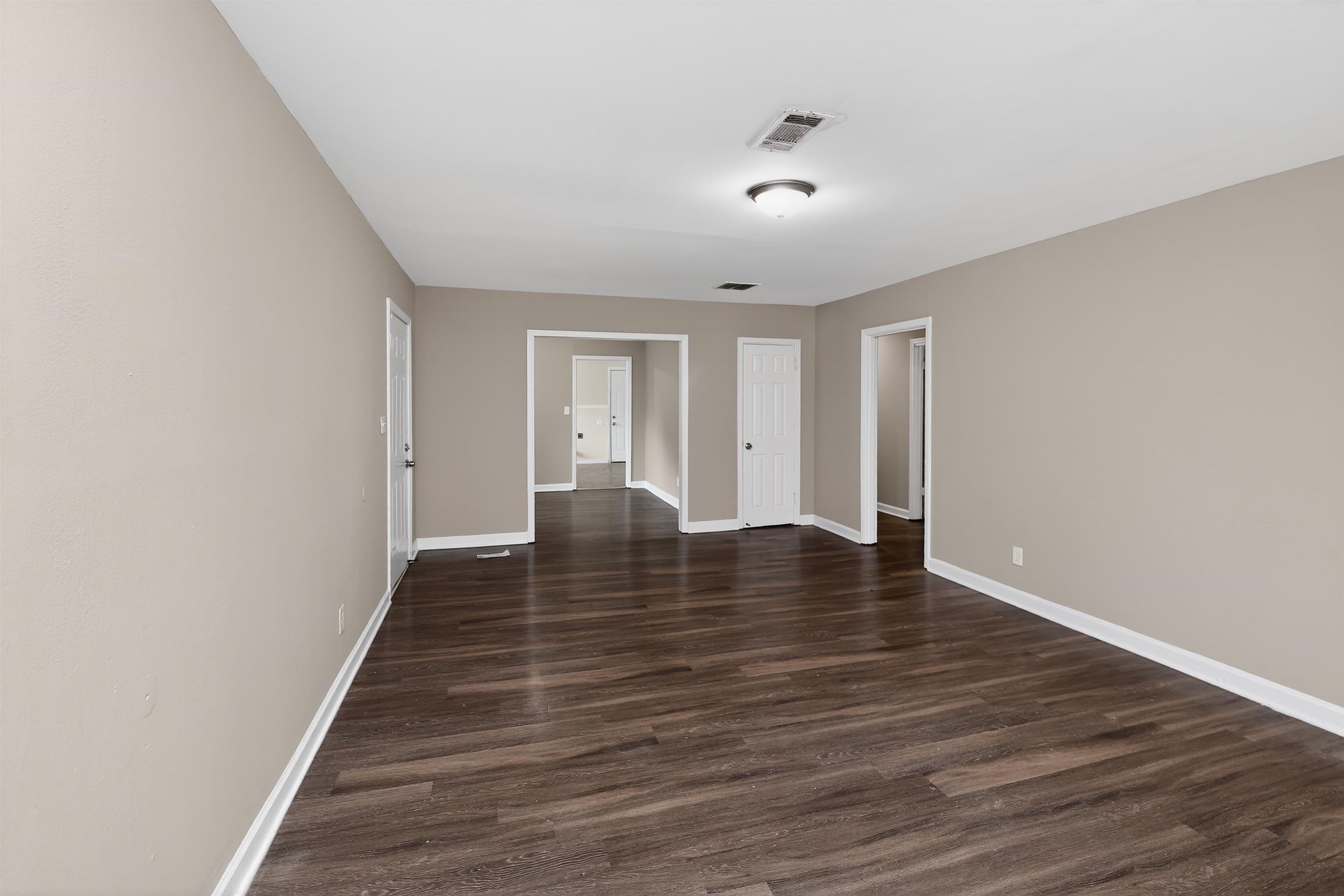 318 East Raines Road Memphis, TN 38109 - Photo 14 of 28 Expansive room featuring wood-finish flooring, light tan wall finishes, white baseboards, and a semi-flush mount ceiling light fixture