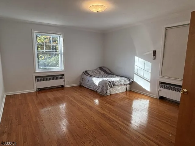 a spacious bedroom with a bed and wooden floor