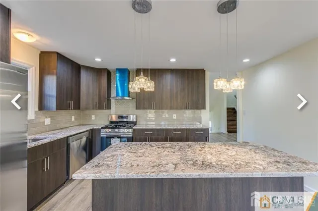 a large kitchen with kitchen island a sink stainless steel appliances and a counter top space