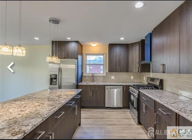 a kitchen with stainless steel appliances granite countertop wooden cabinets and sink