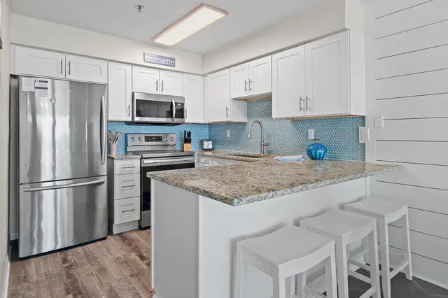 a kitchen with granite countertop a refrigerator a sink a stove a microwave and wooden floor