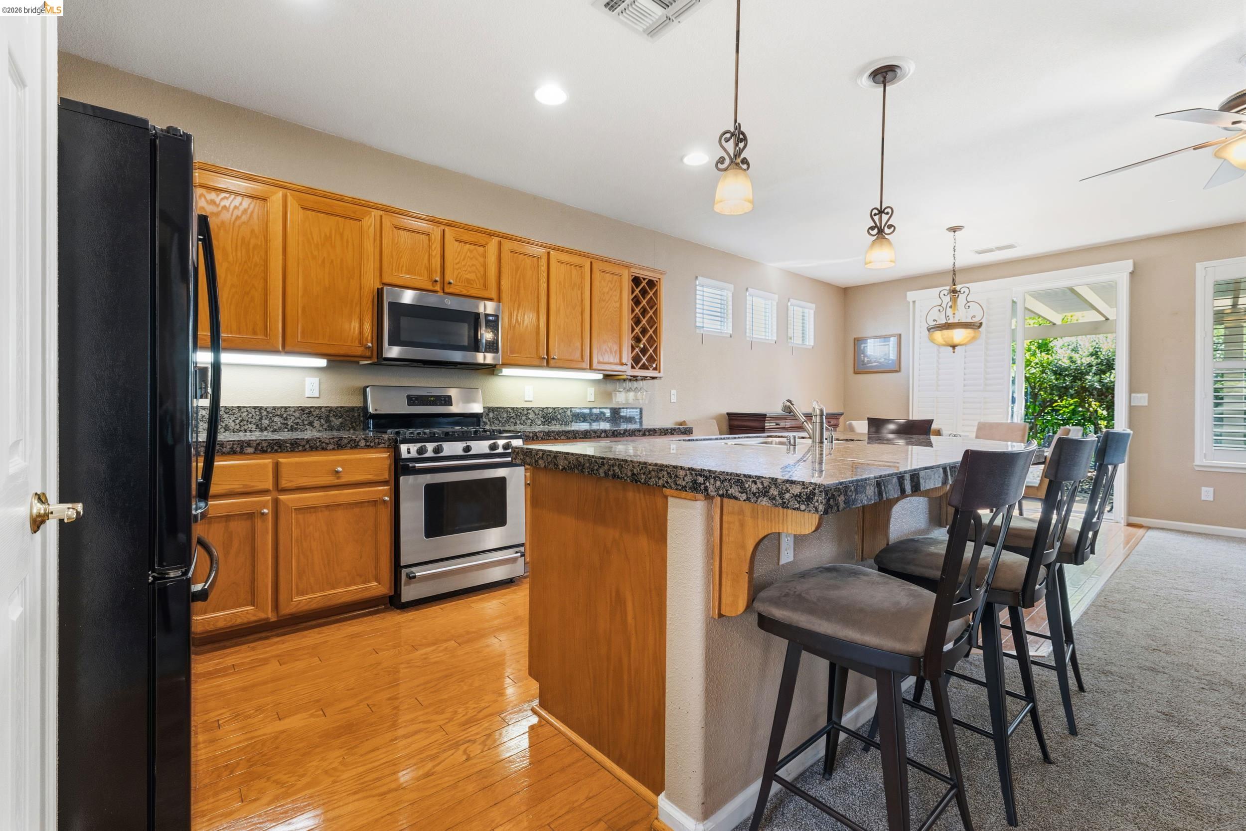 1063 Waterwood Drive Rio Vista, CA 94571 - Photo 11 of 38 a kitchen with stainless steel appliances granite countertop a stove top oven a sink a dining table and chairs with wooden floor