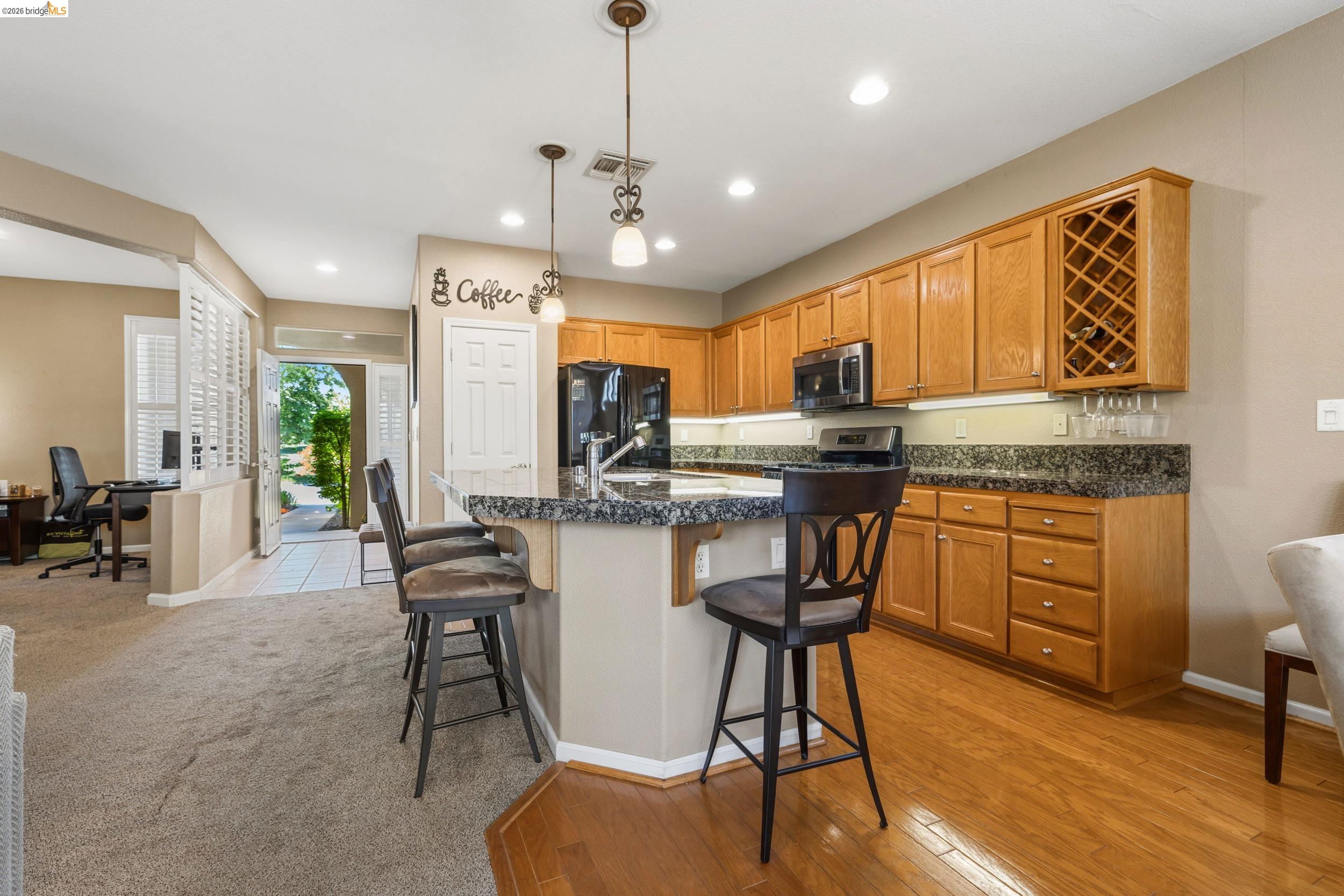 1063 Waterwood Drive Rio Vista, CA 94571 - Photo 12 of 38 a kitchen with stainless steel appliances granite countertop a stove top oven a sink a dining table and chairs with wooden floor