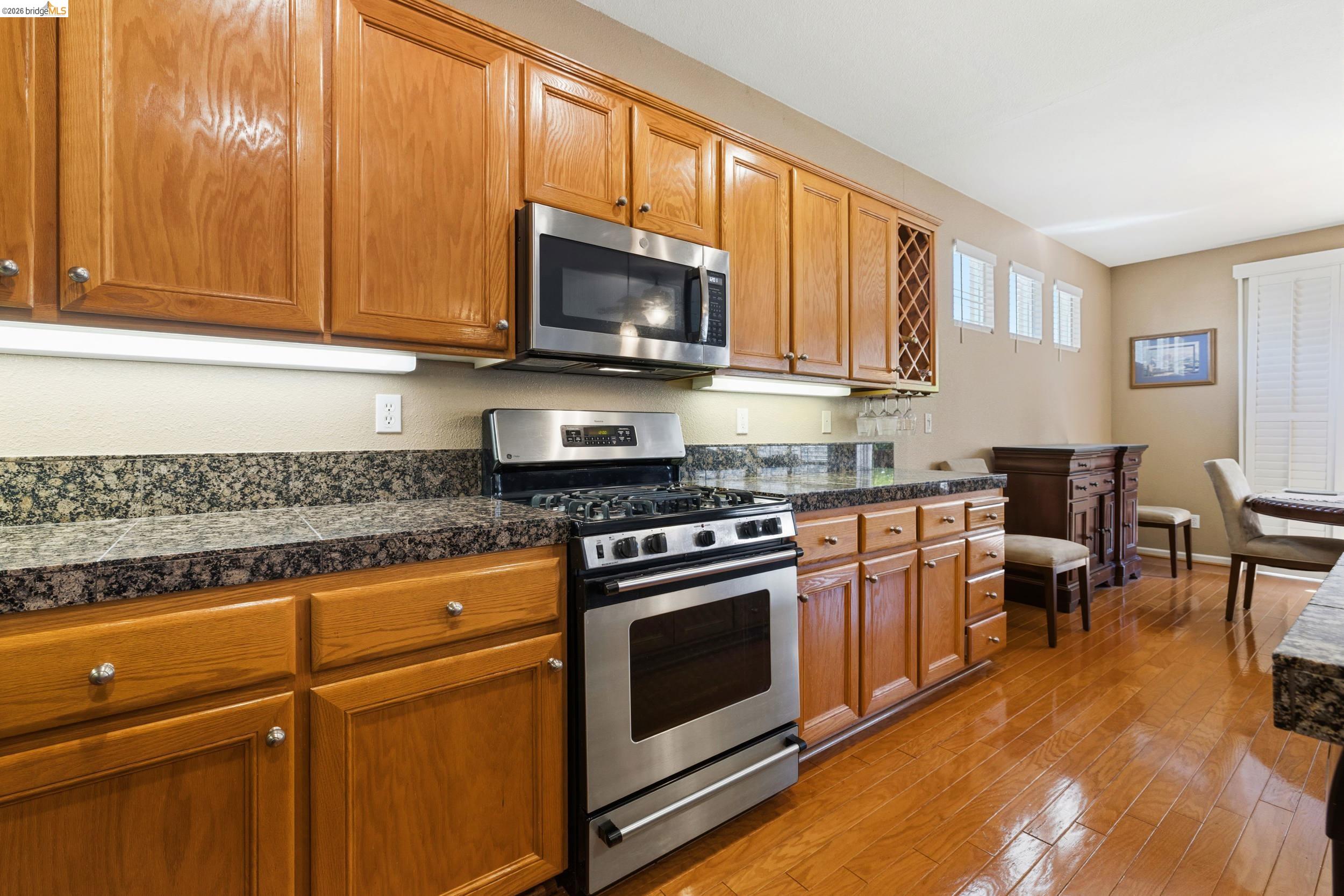 1063 Waterwood Drive Rio Vista, CA 94571 - Photo 16 of 38 a kitchen with stainless steel appliances granite countertop a stove top oven a sink dishwasher a dining table and chairs with wooden floor