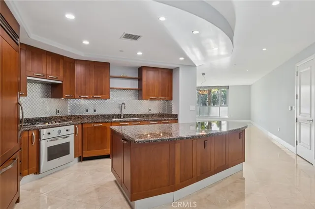 a kitchen with stainless steel appliances granite countertop a stove a sink and a refrigerator