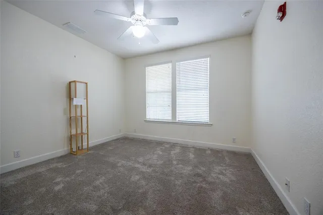 an empty room with a window and a ceiling fan