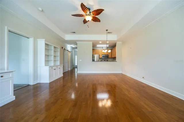 an empty room with wooden floor and a ceiling fan