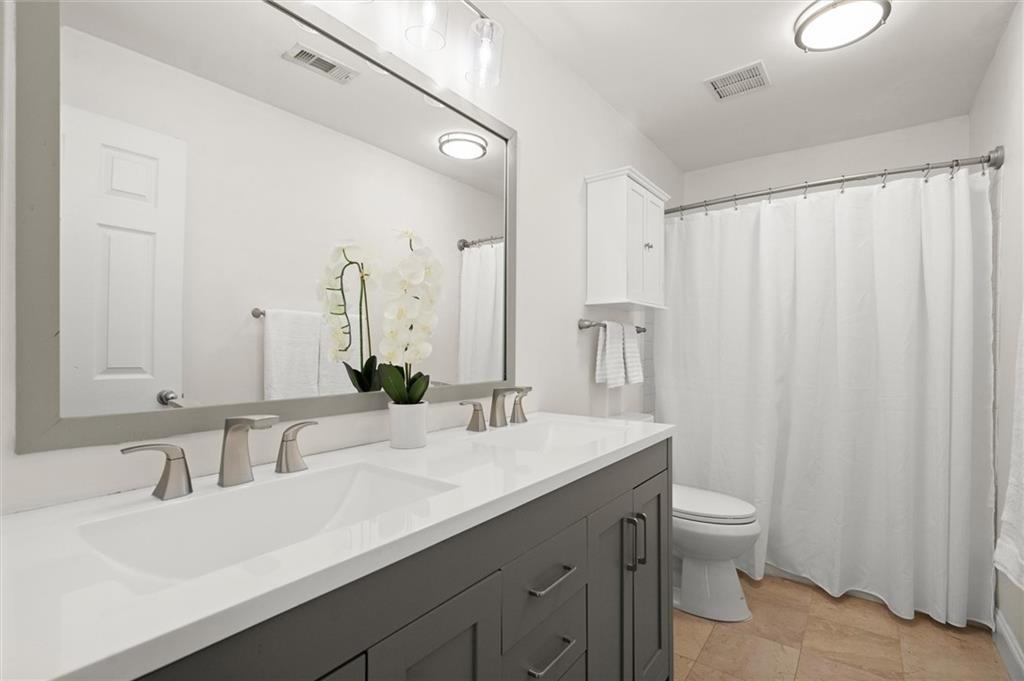 6980 Roswell Road, Unit F7 Atlanta, GA 30328 - Photo 28 of 43 a bathroom with a double vanity sink toilet and a mirror