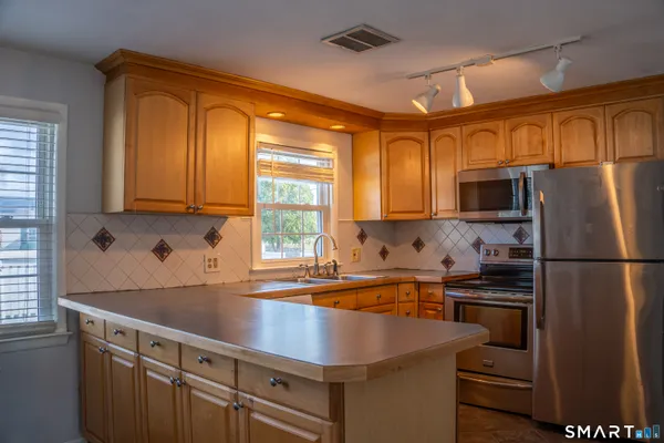 a kitchen with stainless steel appliances a sink cabinets and a window