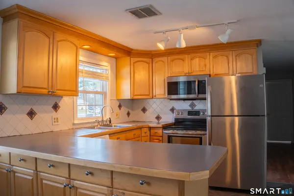 a kitchen with stainless steel appliances a refrigerator a sink a stove and cabinets