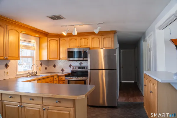 a kitchen with stainless steel appliances a refrigerator a sink a stove and white cabinets