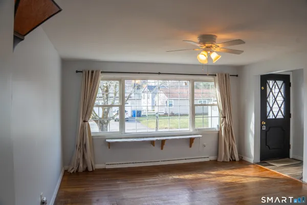 a view of an empty room with a window and wooden floor