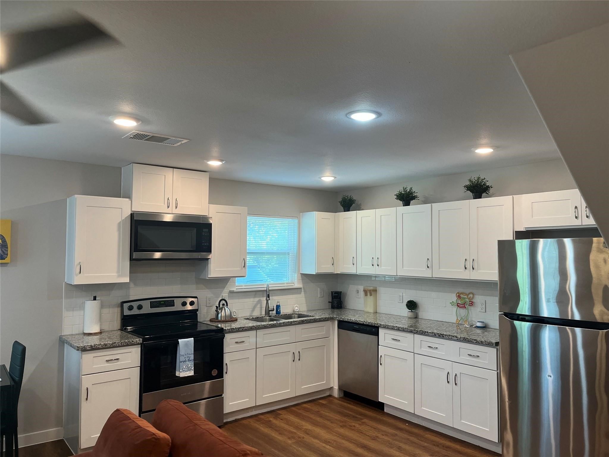 a kitchen with granite countertop a refrigerator stove top oven and sink