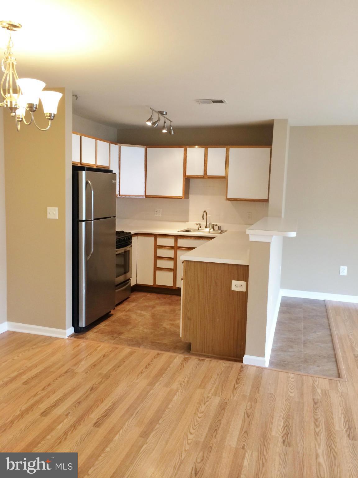 635 Constellation Square Southeast, Unit E Leesburg, VA 20175 - Photo 6 of 20 a kitchen with stainless steel appliances granite countertop a refrigerator a sink dishwasher a stove with wooden floor
