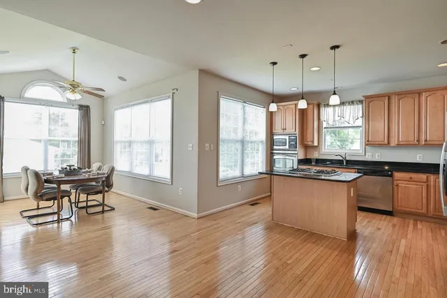 a kitchen with stainless steel appliances granite countertop wooden floors and white cabinets