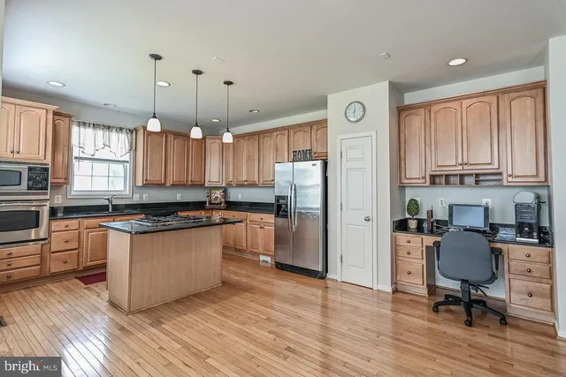 a kitchen with granite countertop a refrigerator a stove a sink cabinets and wooden floor