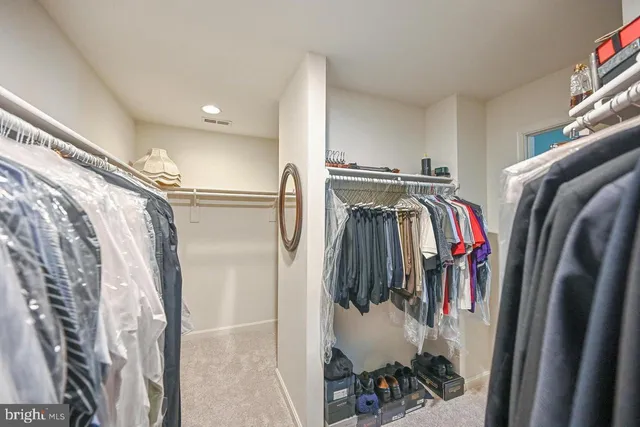 a view of walk in closet with clothes and shoes