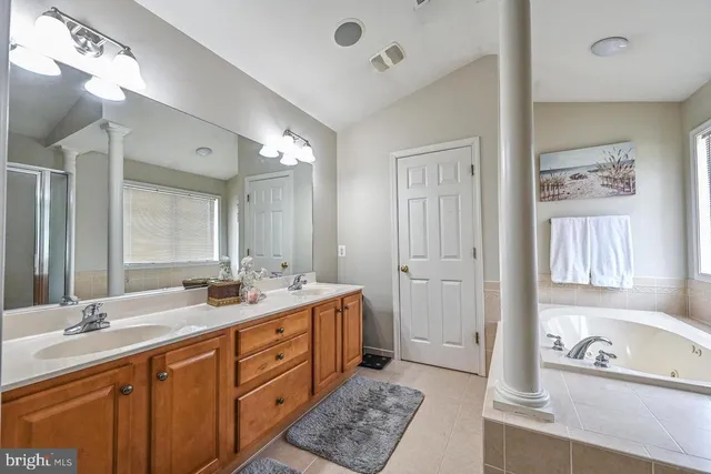 a spacious bathroom with a double vanity sink double mirror and bathtub