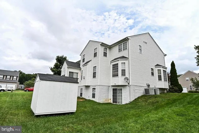 a view of a white house with a big yard and large trees