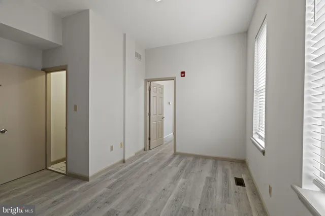 an empty room with wooden floor and windows