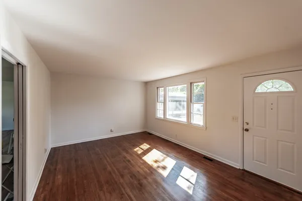 an empty room with wooden floor and window