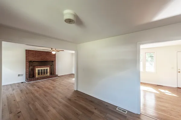 an empty room with wooden floor chandelier fan and windows