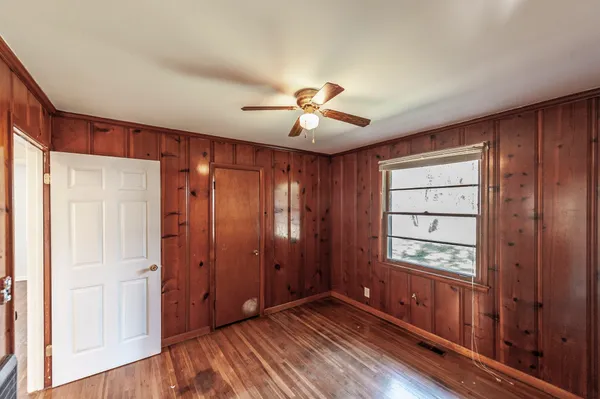 a view of an empty room with wooden floor and a window